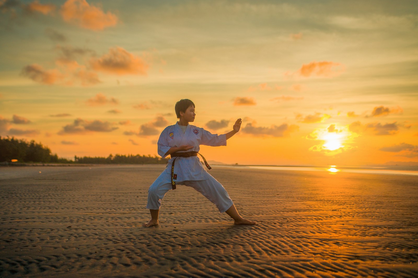 Practicante de karate haciendo un kata al atardecer en la playa